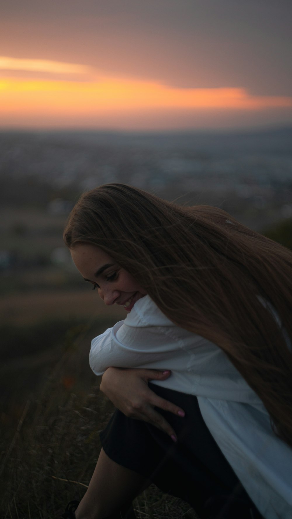 a woman with long hair sitting in a field