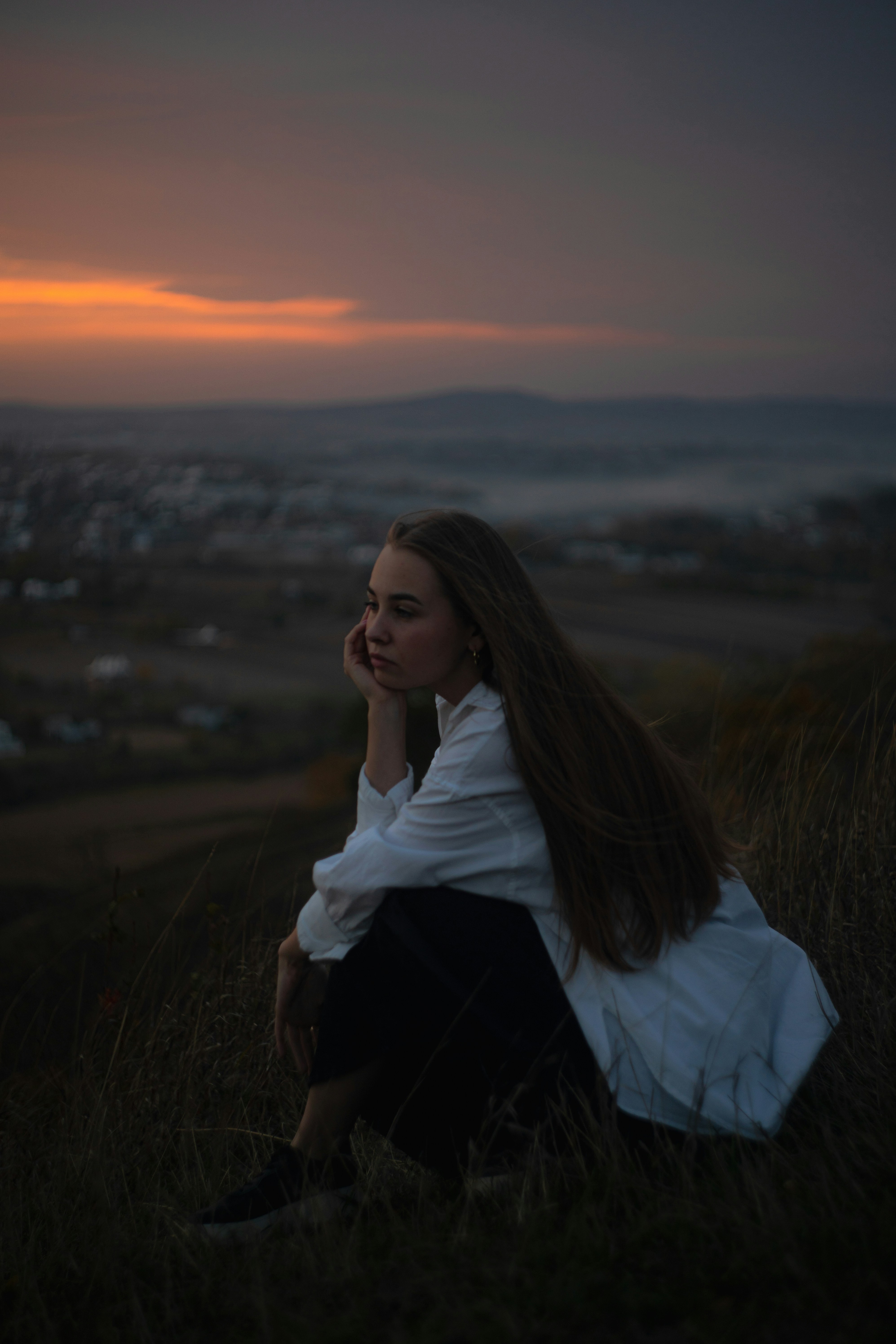 a woman sitting on top of a grass covered hillside
