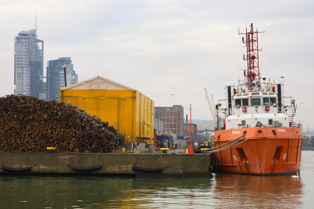 a boat is docked next to a pile of wood