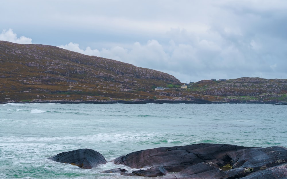 a large body of water sitting next to a lush green hillside