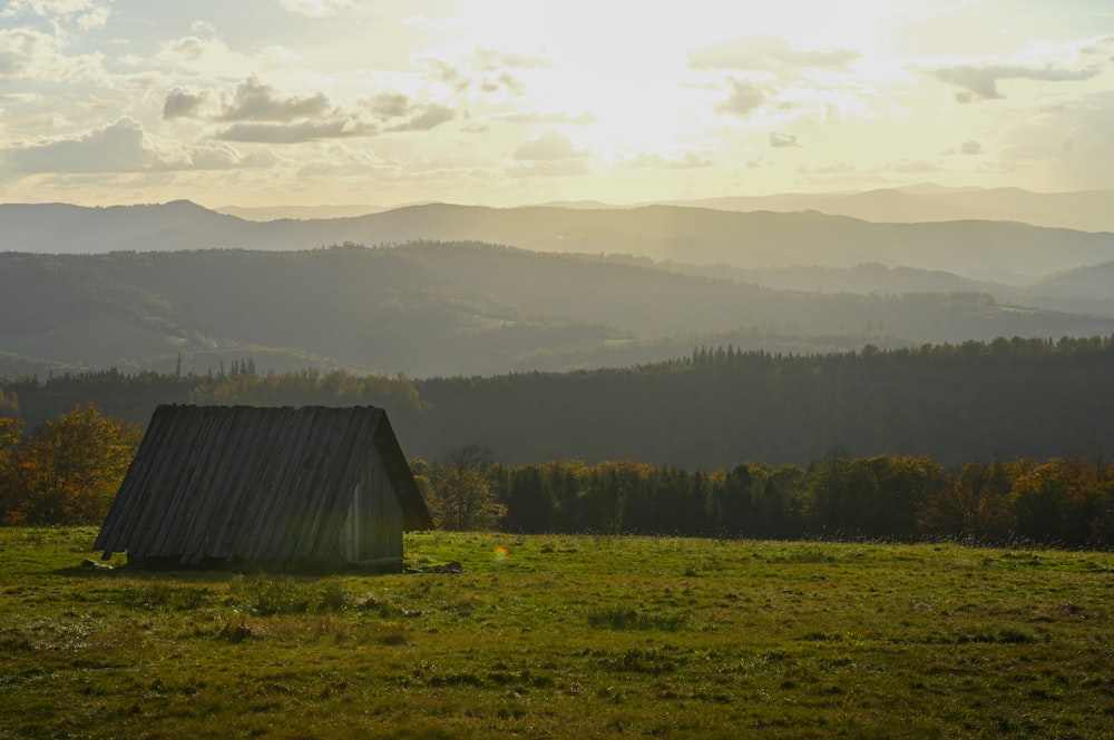 a barn in a field with mountains in the background