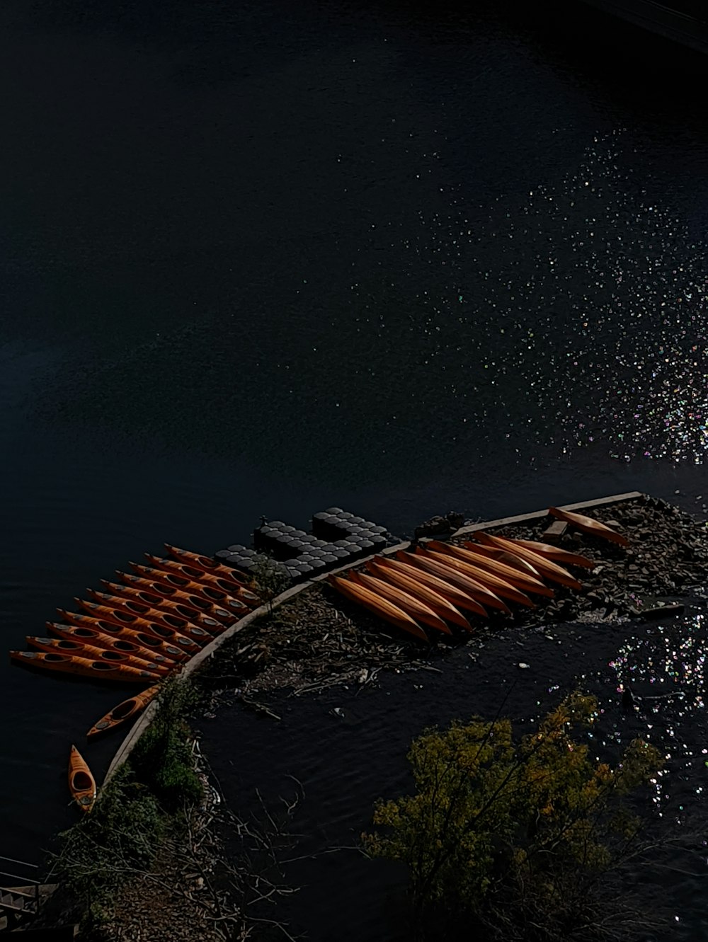a row of canoes sitting on the shore of a lake