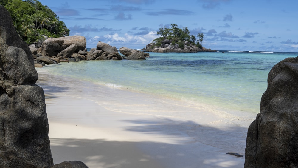 a beach with rocks and clear blue water