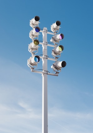 A tall pole with multiple round, camera-like devices attached on either side, situated against a clear blue sky.