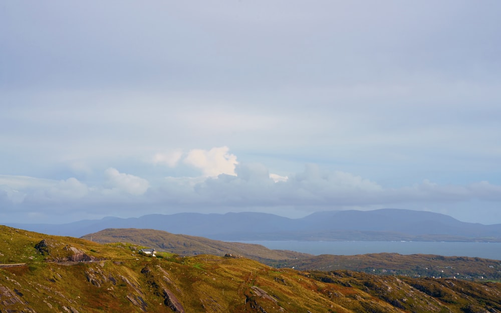 a grassy hill with a body of water in the distance