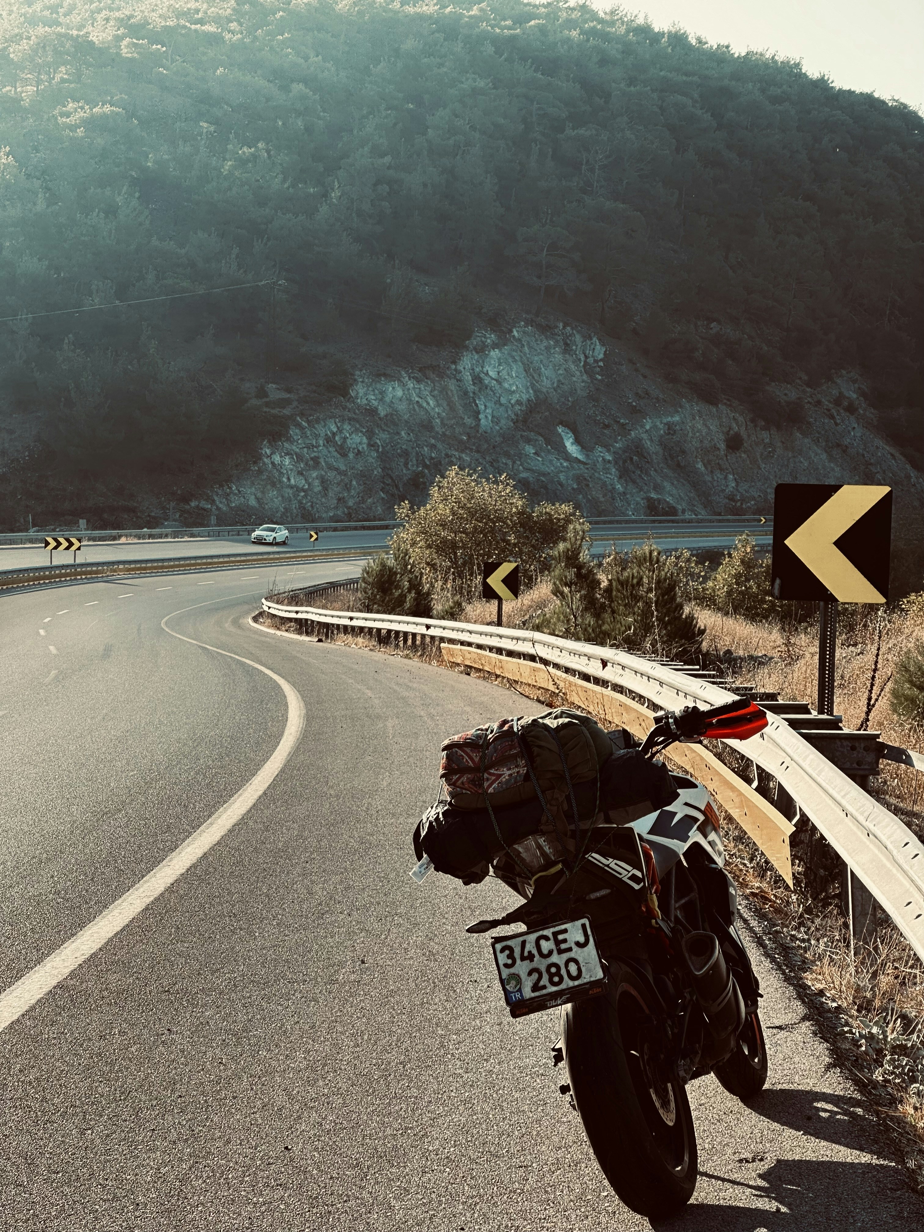 Loaded motorcycle parked on the shoulder of a mountain road.