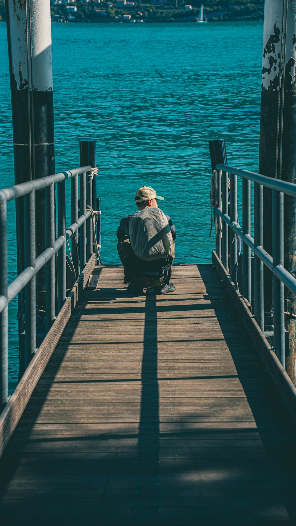 a man sitting on a dock looking out at the water