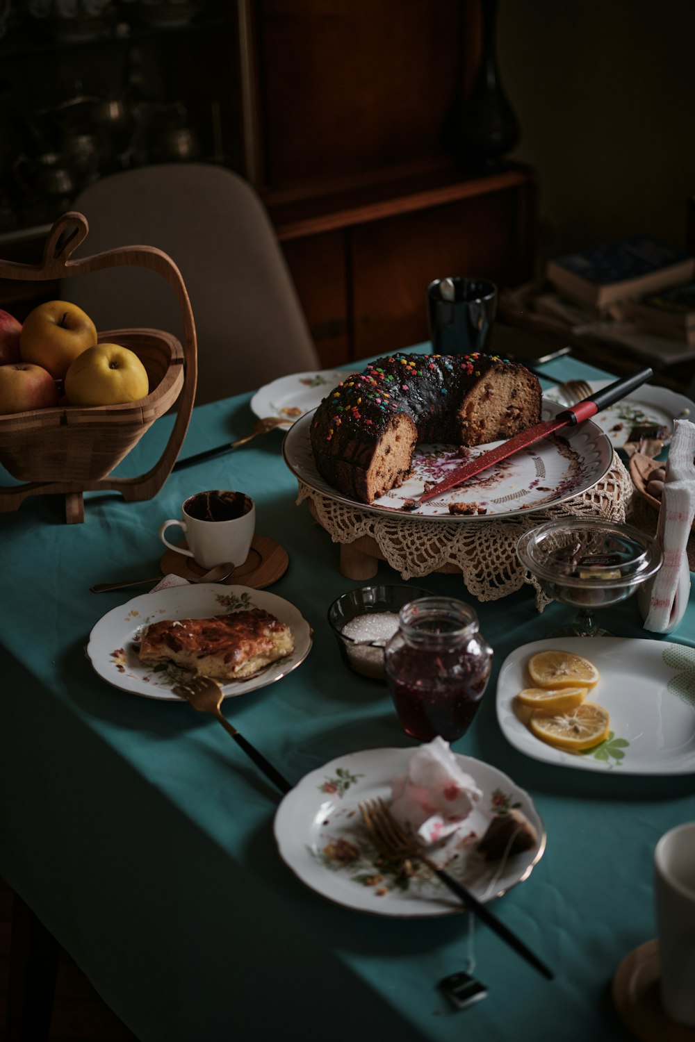 a table topped with plates of food and a basket of fruit