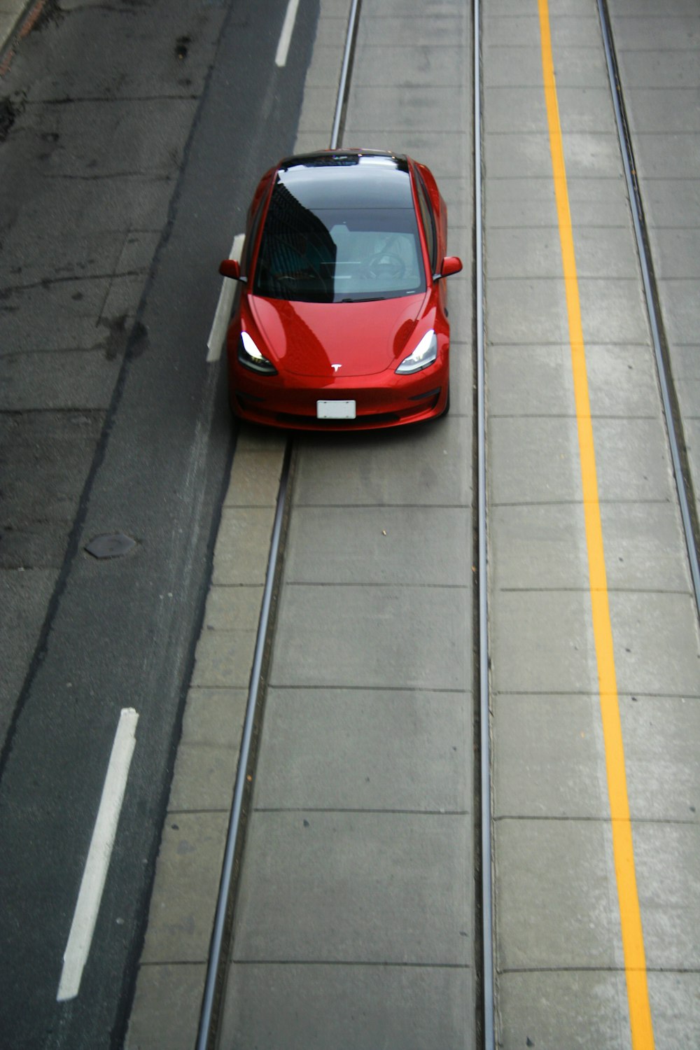 a red car driving down a street next to a yellow line