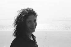a black and white photo of a woman on the beach