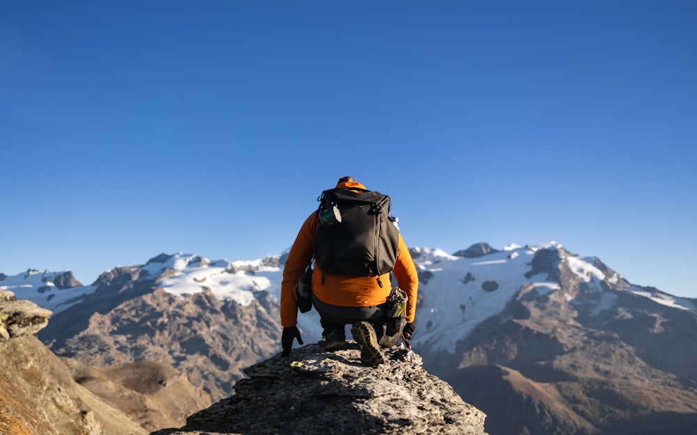 a man sitting on top of a mountain with a backpack
