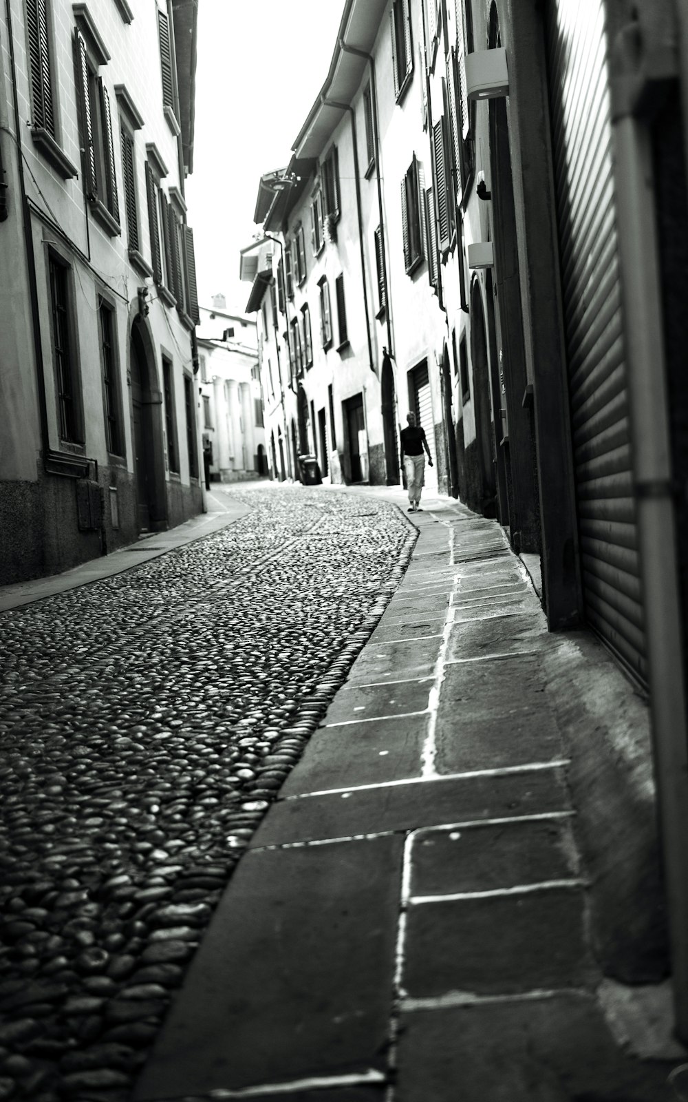 a person is walking down a cobblestone street