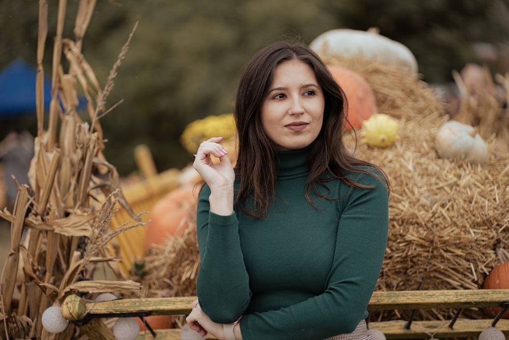 a woman standing in front of a pile of hay