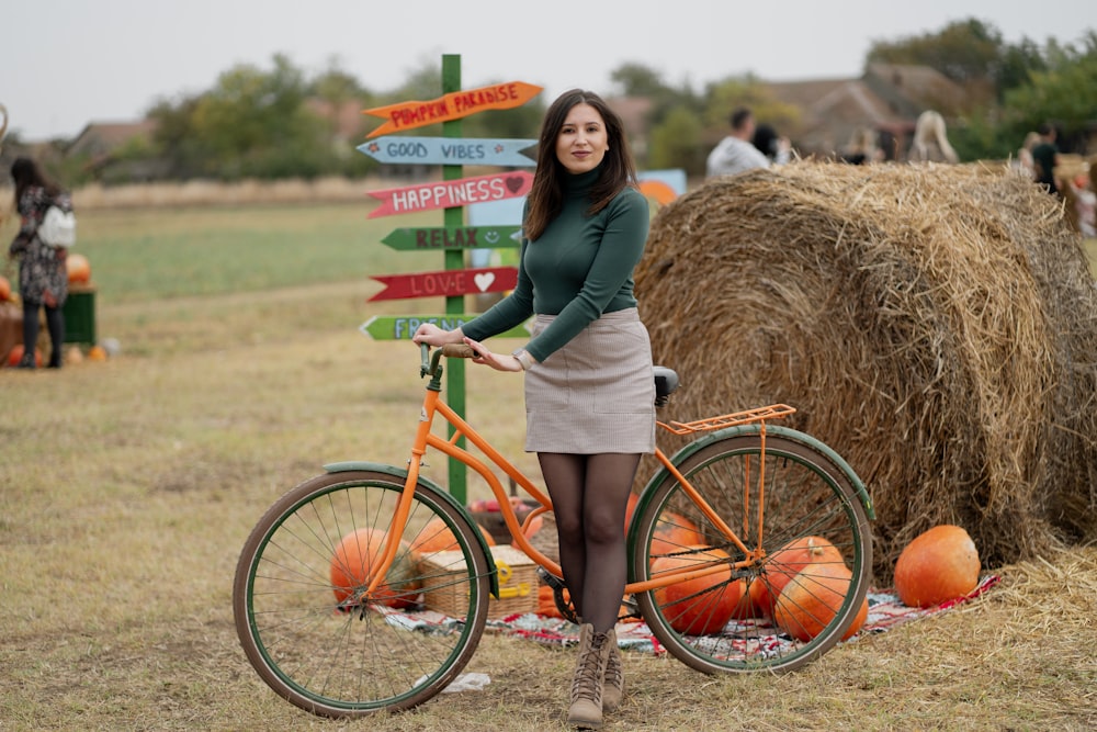 uma mulher ao lado de uma bicicleta ao lado de um fardo de feno