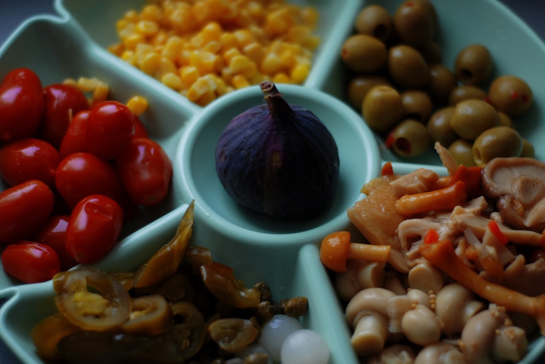 a plate of food that includes olives, tomatoes, corn, and beans