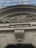 A detailed architectural bas-relief shows a skeleton amidst elaborate foliage, positioned above a building entrance. Below the relief is an inscription in gold lettering on a dark background reading 'SPES ALTERA VITÆ'. The surrounding structure features classic architectural elements in beige tones.