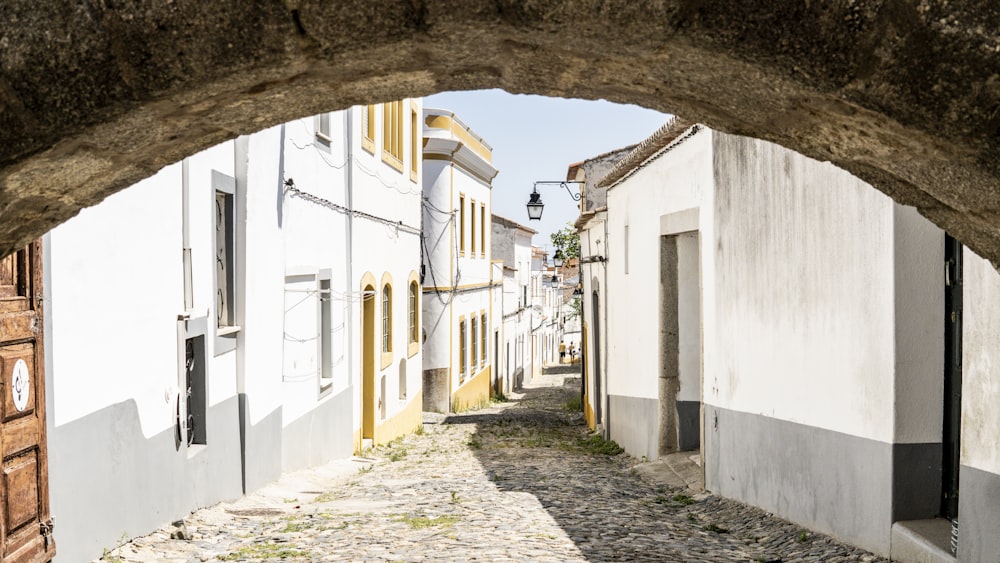 a narrow cobblestone street with white buildings