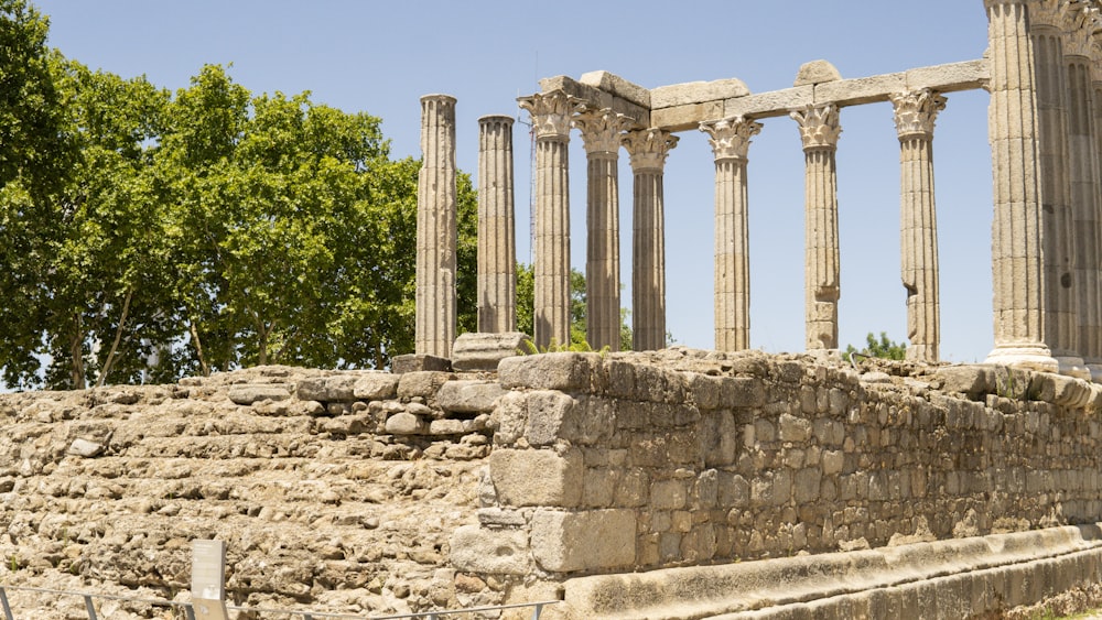 a stone wall with columns and trees in the background