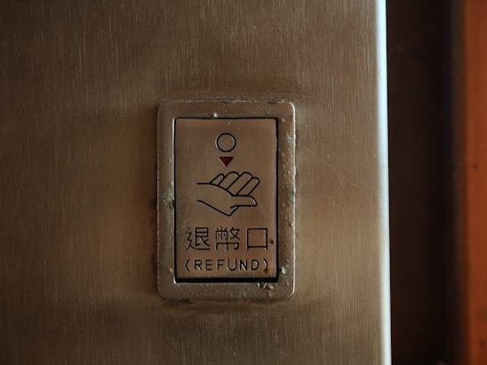 A metal panel with a sign depicting a hand and a coin above it. Below the illustration, there are Chinese characters and the word 'REFUND' in English.