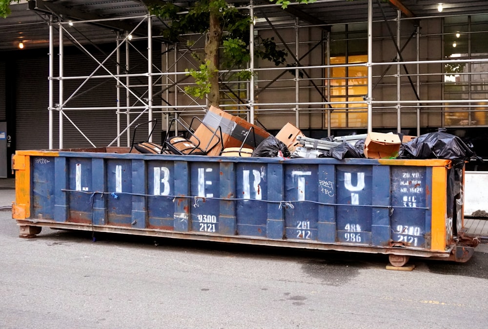 a blue and orange trailer with a pile of junk on top of it