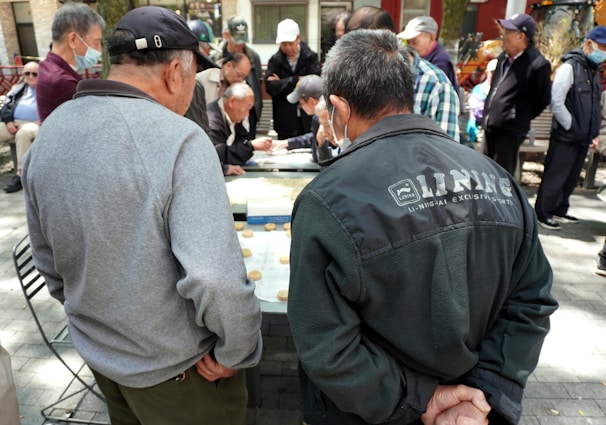 A group of retired adults laughing and chatting on the sidelines with paddles in hand