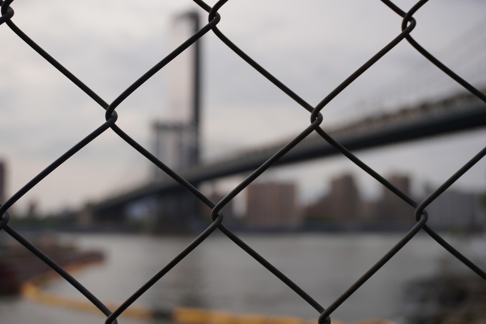 a chain link fence with a city in the background
