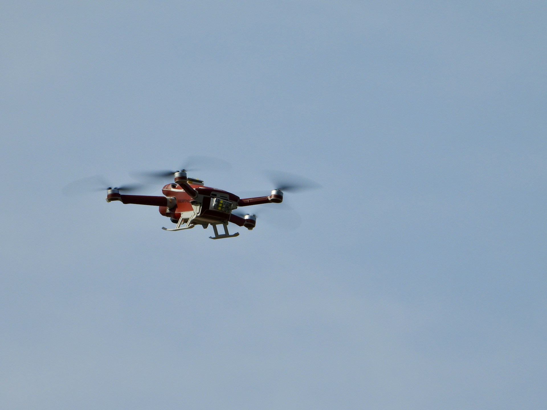 a red and white helicopter flying through a blue sky