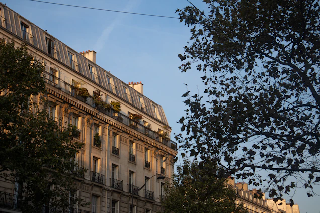 A sunlit Roman apartment balcony overlooking cobblestone streets and historic buildings.