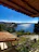 Cozy seaside vacation home with vibrant flowers and a view of the sparkling blue sea at sunset.