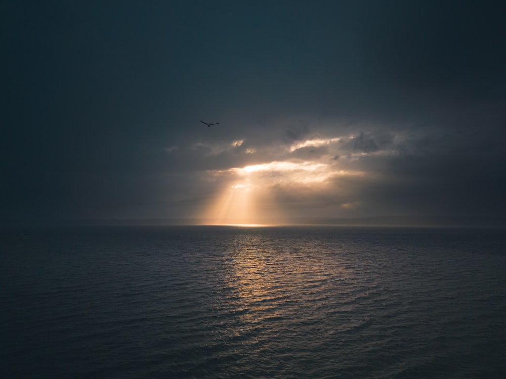 the sun is shining through the clouds over the ocean