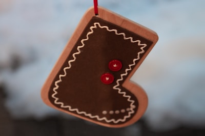 A white stocking tag with a red layered heart design, attached to a plush stocking suspended from a stone fireplace.