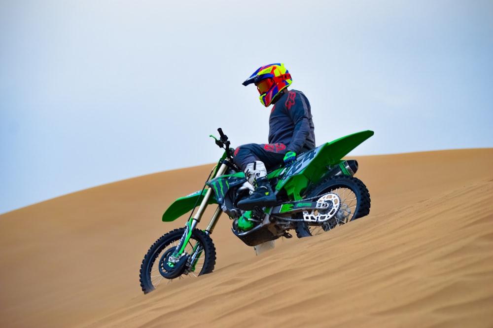 a man riding a dirt bike on top of a sandy hill