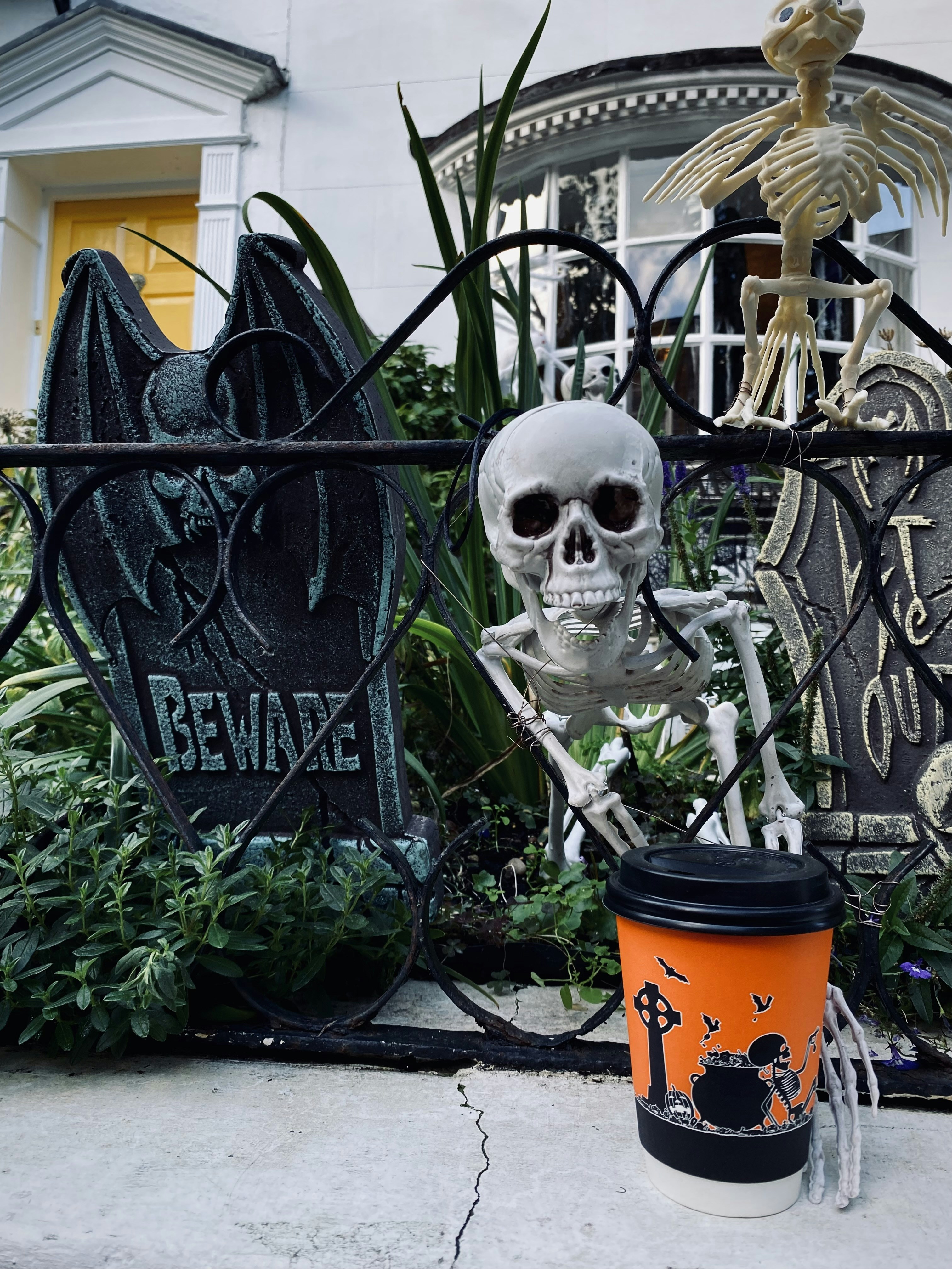 una taza de café sentada junto a una estatua de esqueleto