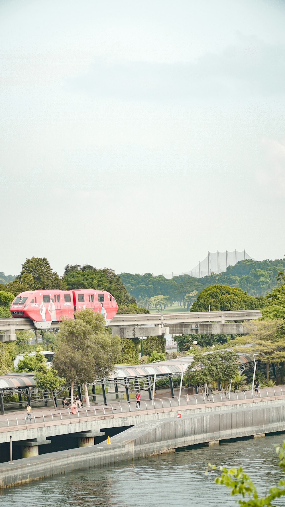 a red train traveling over a bridge next to a river