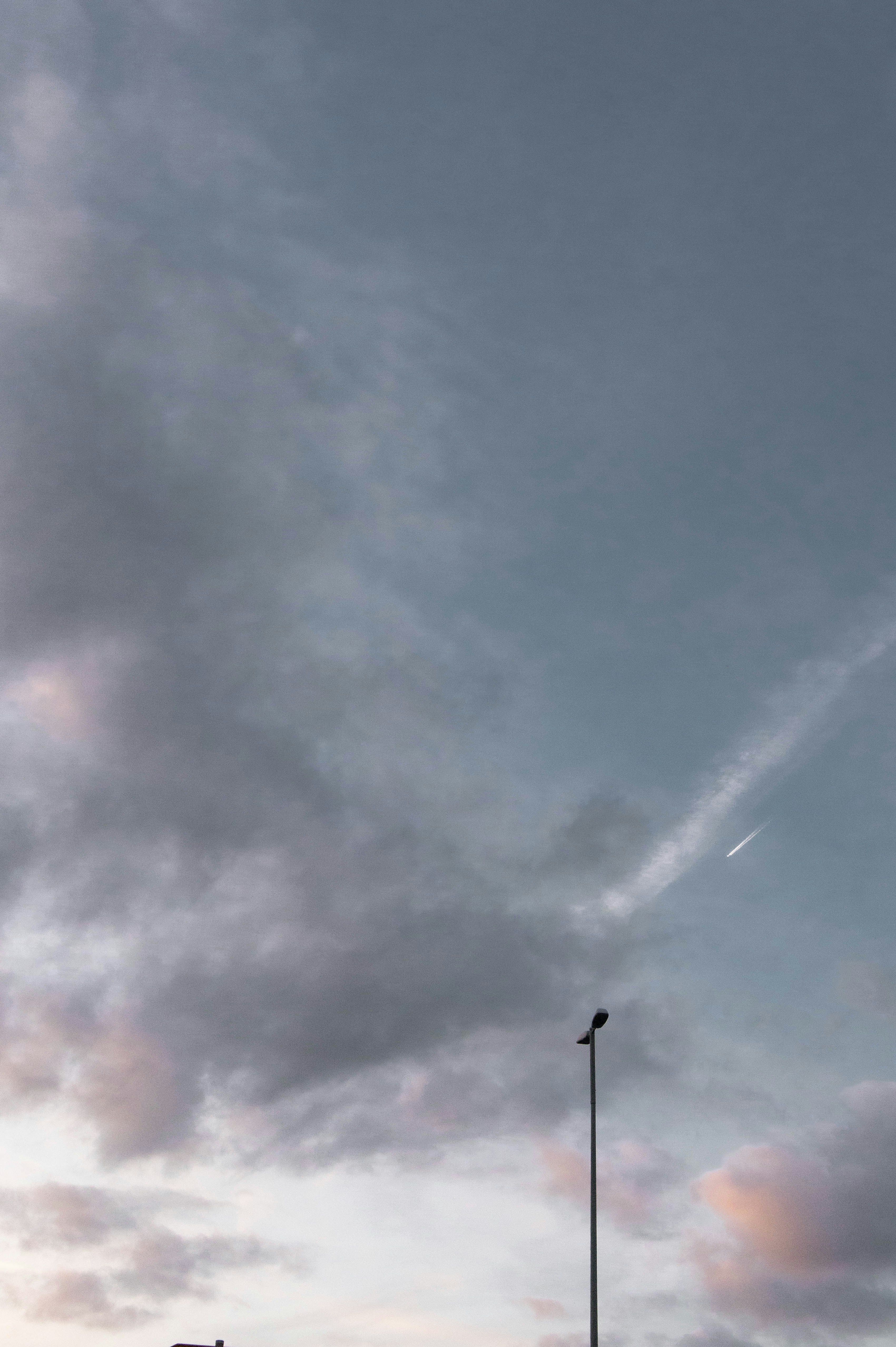 an airplane flying in a cloudy sky with a street light