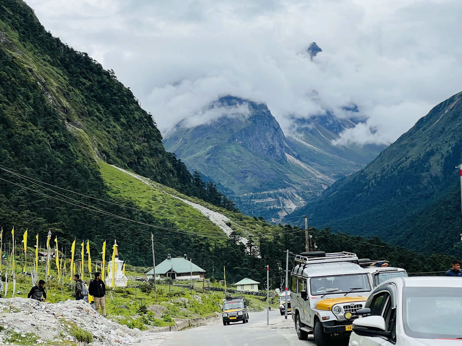 Hired four wheel drives on the mountain road at Yumthang in North Sikkim, prayer flag poles beside it