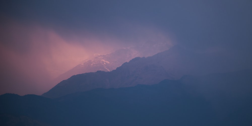 a view of a mountain covered in snow under a cloudy sky