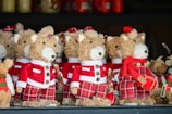 A collection of straw-crafted festive dog ornaments dressed in red and white Santa Claus outfits, with some wearing hats and others adorned with scarves. They feature button eyes and black noses, standing together on a shelf as part of holiday decorations.