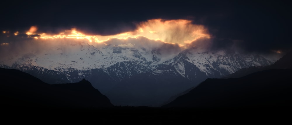 the sun is shining through the clouds over the mountains