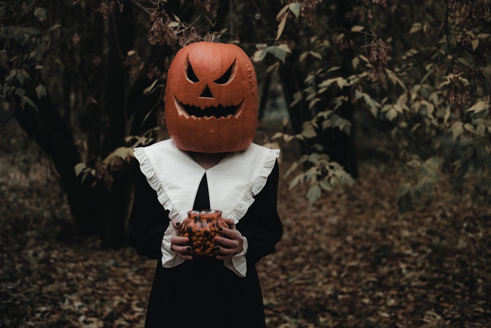 a person wearing a pumpkin mask holding something in their hands
