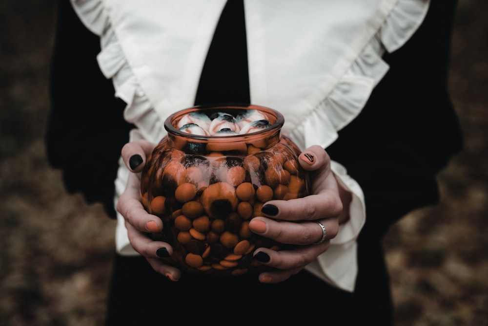a woman holding a vase filled with lots of nuts