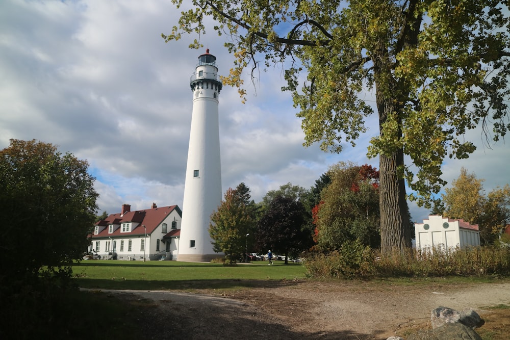 a large white light house sitting next to a tree