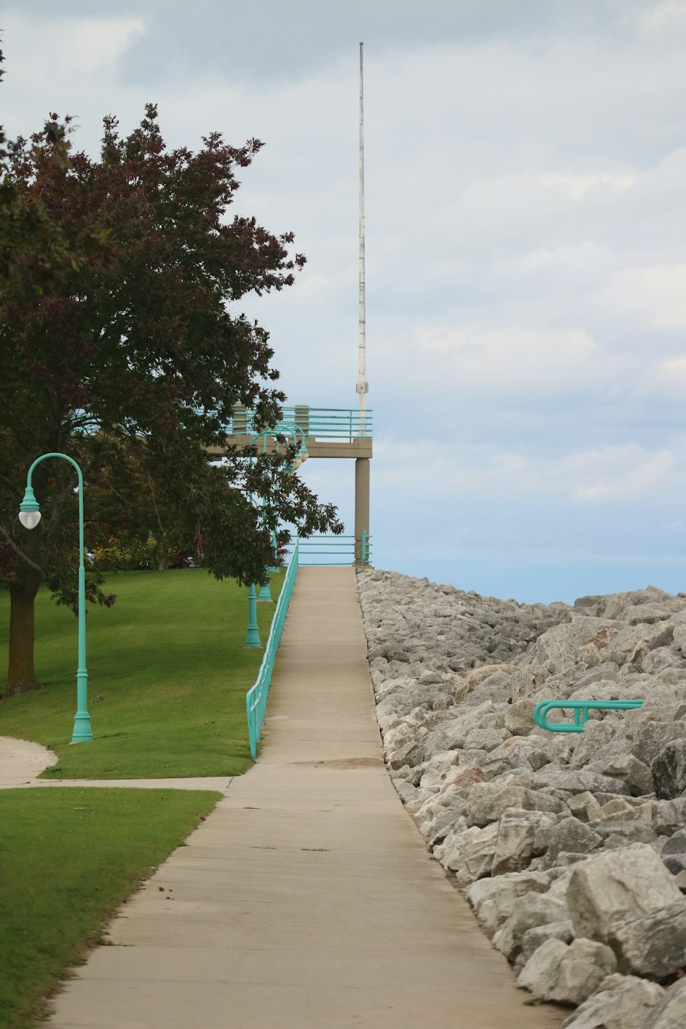a walkway leading to a light house on a cloudy day