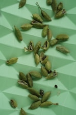 Hands carefully selecting fresh cardamom pods from a harvest basket.