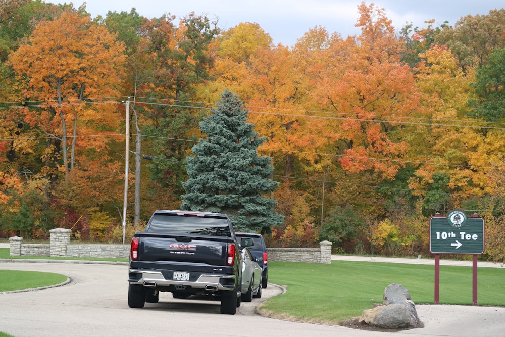 a black truck driving down a road next to a forest