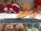 Several exotic fruits are displayed on a supermarket shelf. There are cut pieces of dragon fruits with dark seeds and vibrant pink flesh, as well as slices of papaya. A handwritten sign notes 'Sweet Papaya: 29,90' alongside a request not to squeeze the papayas. Below the fruits, packages of brown mushrooms are visible, and a box of Jolly Time popcorn is partly seen on the side.