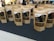 Several brown paper bags with clear windows displaying dried worms are arranged on a dark surface. The bags are labeled with text and graphics, likely indicating the product and brand name. In the background, blurred figures and a bright interior are visible, suggesting a market or exhibition setting.