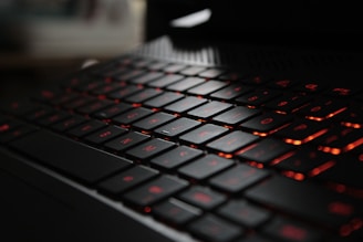 Close-up of a sophisticated black laptop keyboard illuminated by soft ambient light.