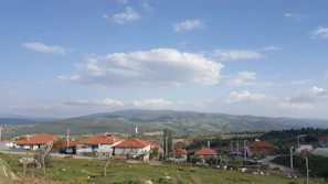 A peaceful plot with a view of distant houses and a bright sky.