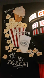 Close-up of a classic popcorn bucket and soda cup illuminated by marquee lights.